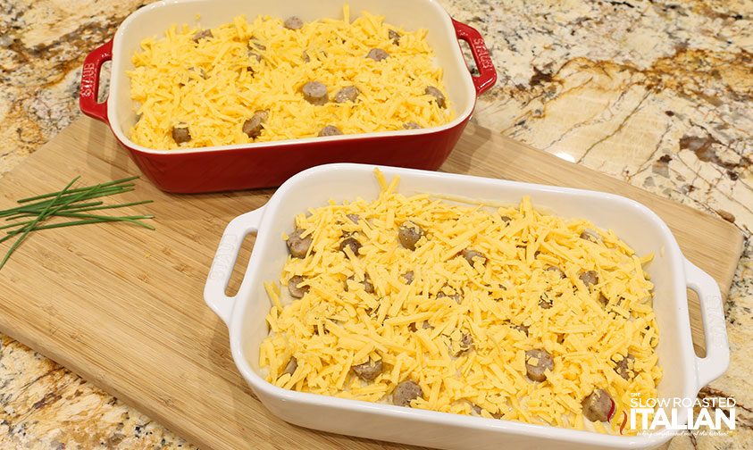 scalloped potatoes with sausage layered in two baking dishes topped with cheese