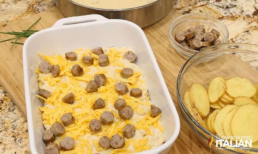 layers of potatoes, sauce, cheese, and sausage in casserole dish