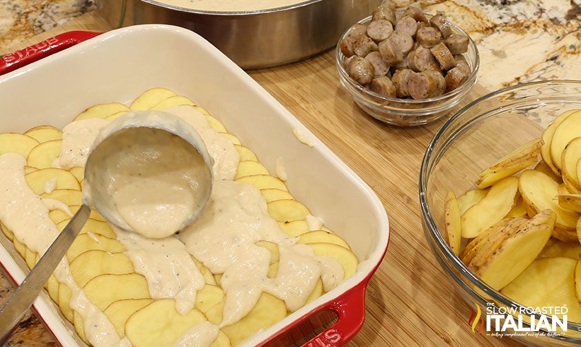 ladling sauce over sliced potatoes in baking dish