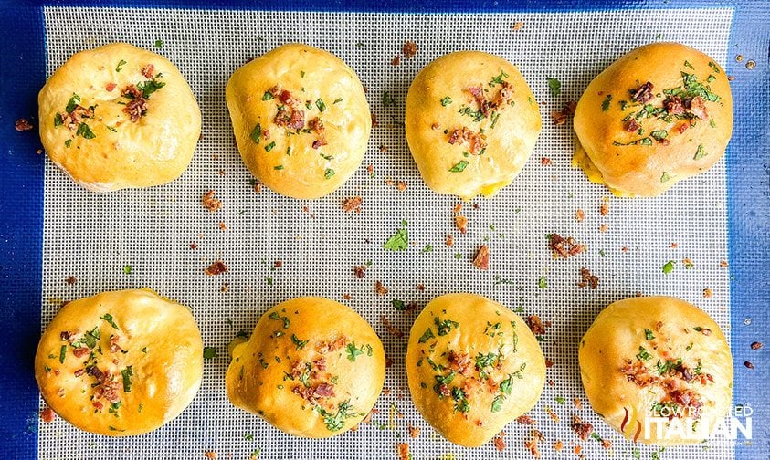 rows of baked mac n cheese bacon bites topped with bacon and parsley