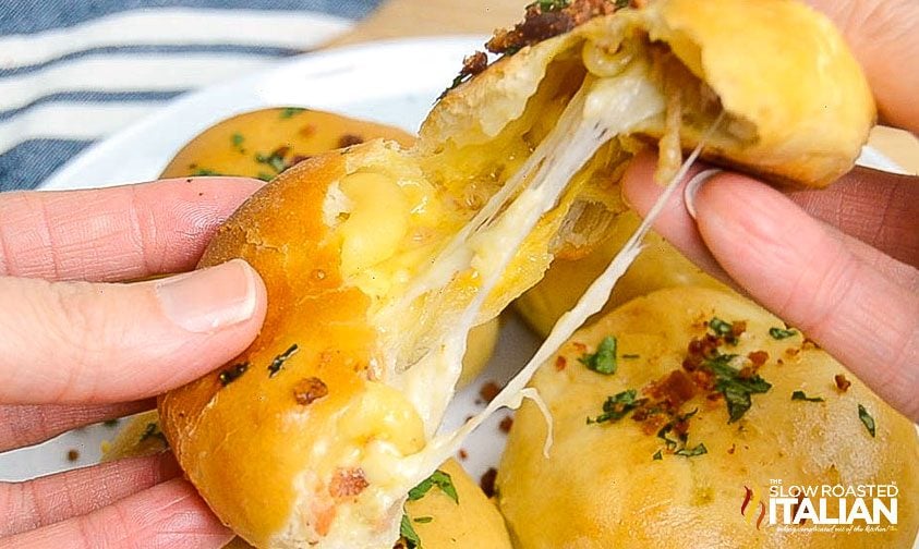 pulling apart bread roll stuffed with mac and cheese and bacon