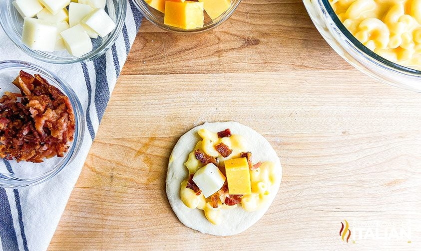 flatted dough ball topped with mac & cheese, bacon pieces, and cubes of cheese