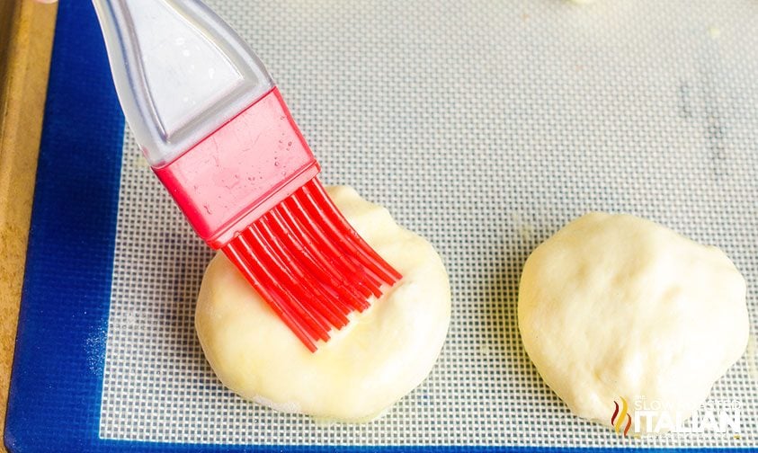 brushing bacon grease over mac and cheese stuffed rolls