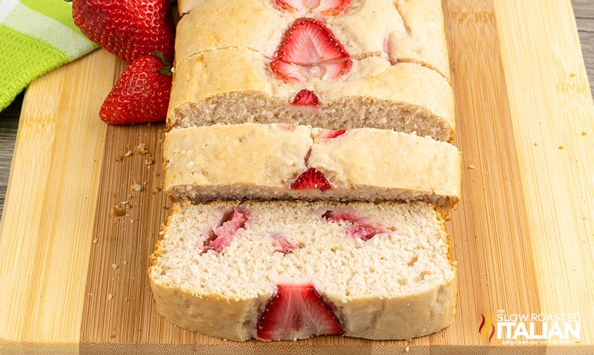 sliced loaf of strawberries & cream bread on a wooden cutting board