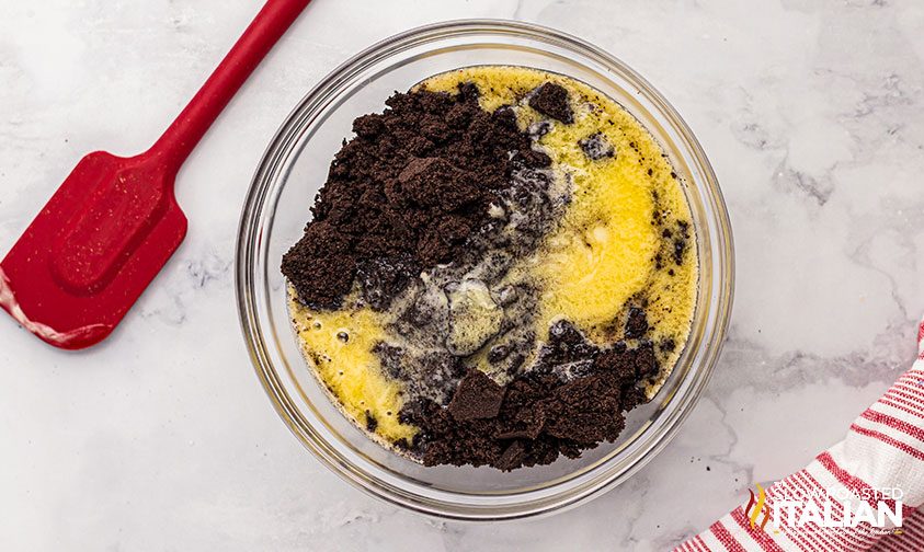 crushed Oreo cookies and melted butter in a bowl