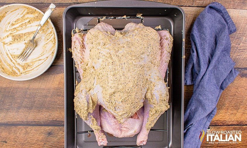 whole turkey slathered in herbed butter in roasting pan