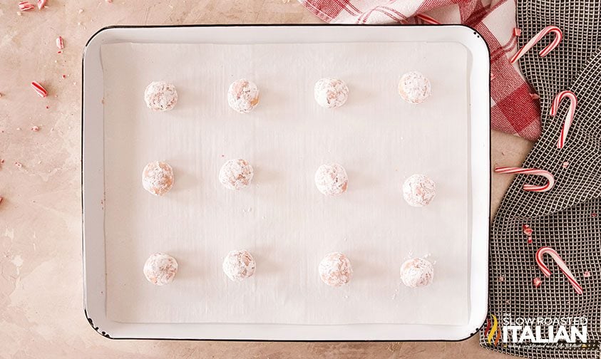 a dozen crinkle cookie dough balls on a parchment lined baking sheet