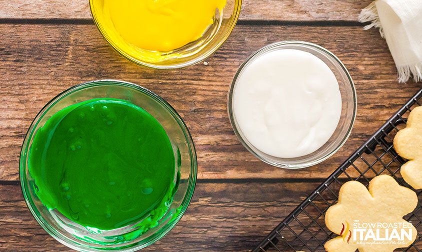 bowls of yellow, white, and green sugar cookie icing