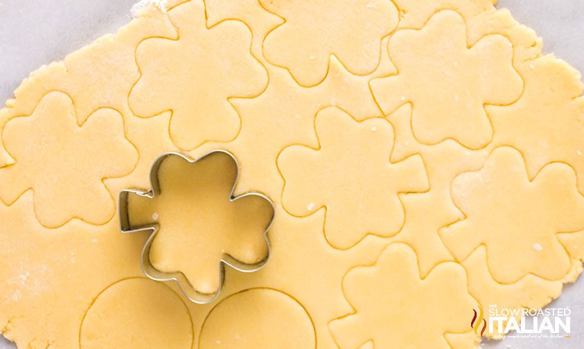 cutting shamrock shapes into sugar cookie dough