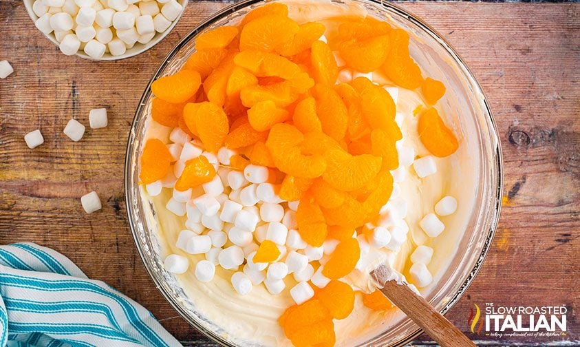 folding mini marshmallows and mandarin oranges into cheesecake mixture