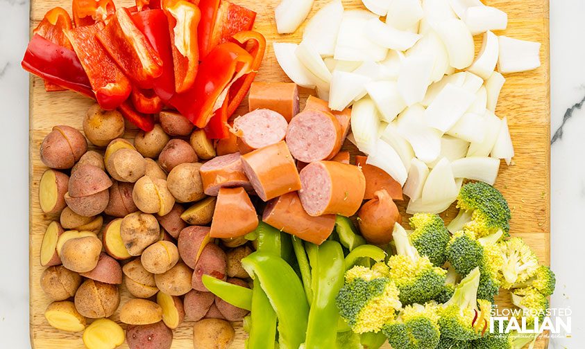 chopped sausage links and vegetables on a cutting board