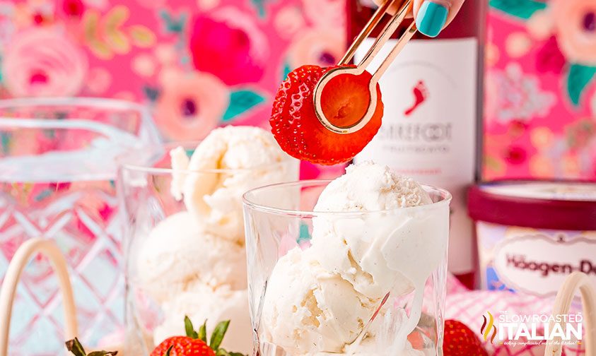 adding strawberry slices to glass of ice cream with tongs