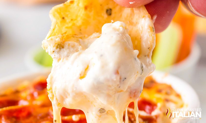 close up: scooping pizza dip with tortilla chip