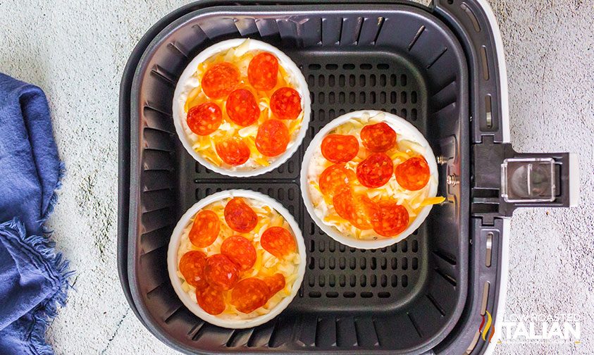 overhead: 3 ramekins of pizza dip in air fryer basket