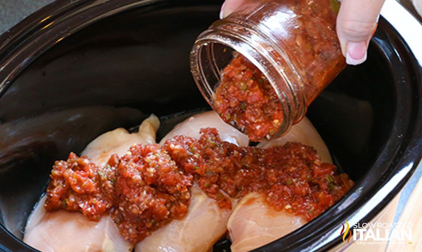 pouring homemade salsa over meat in slow cooker