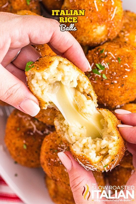 pulling italian rice ball apart, revealing melted cheese in center