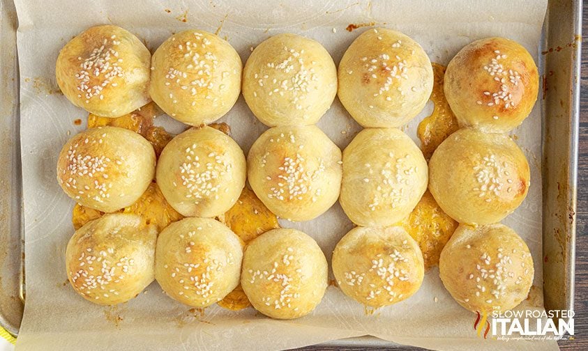 cheeseburger stuffed bread rolls on a parchment-lined baking sheet