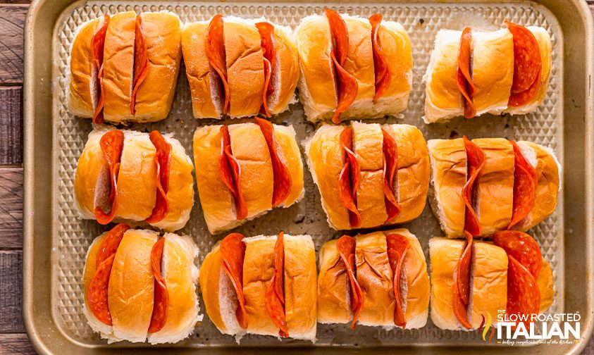 rolls stuffed with pepperoni on baking sheet