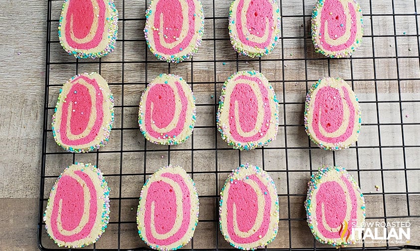 pink swirl cookies coated in sprinkles cooling on wire rack