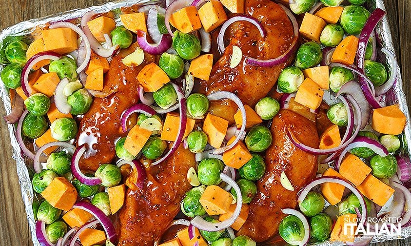 marinated chicken nestled into sheet pan of veggies