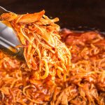 closeup of bbq shredded chicken in tongs