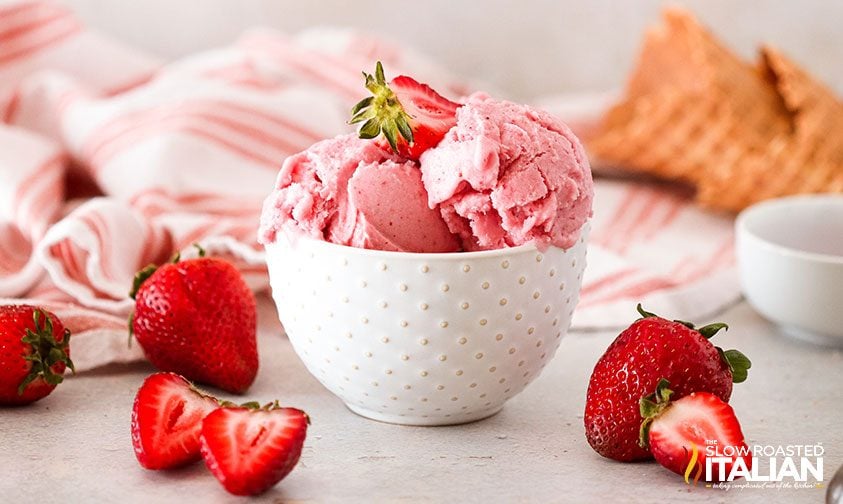 small bowl of strawberry ice cream surround by berries