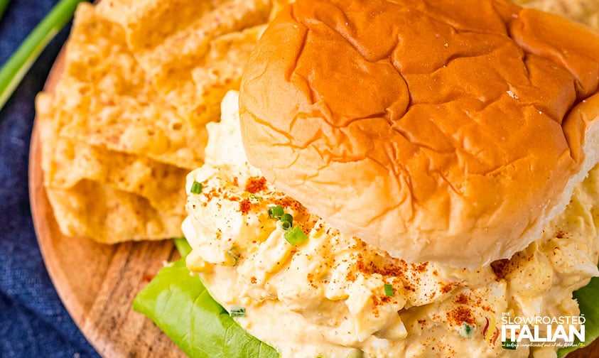 Overhead shot of a chicken salad sandwich on a plate with chips
