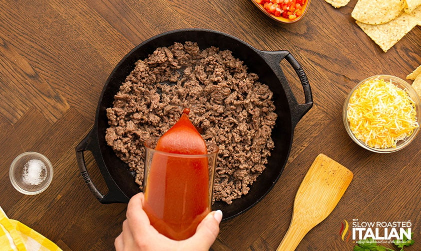 adding enchilada sauce to cooked ground beef