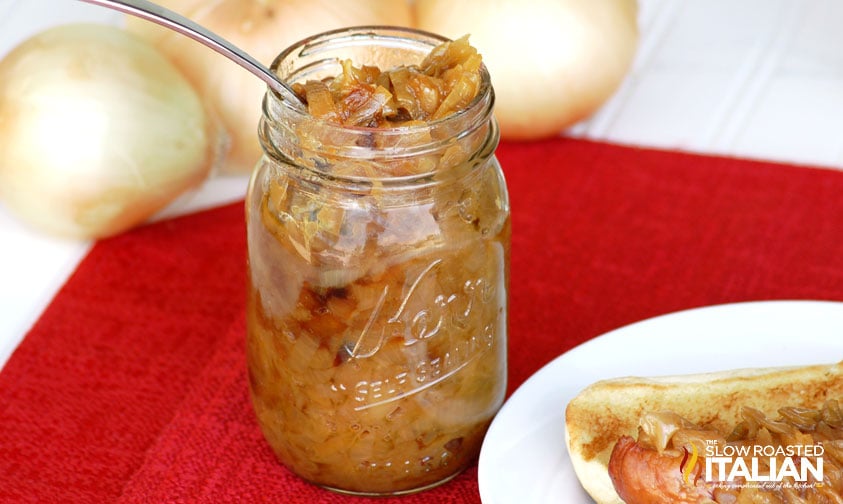 fork in a jar of caramelized onions with a sandwich off to the side