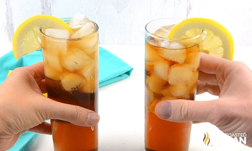 holding two glasses of long island iced tea with lemon slices