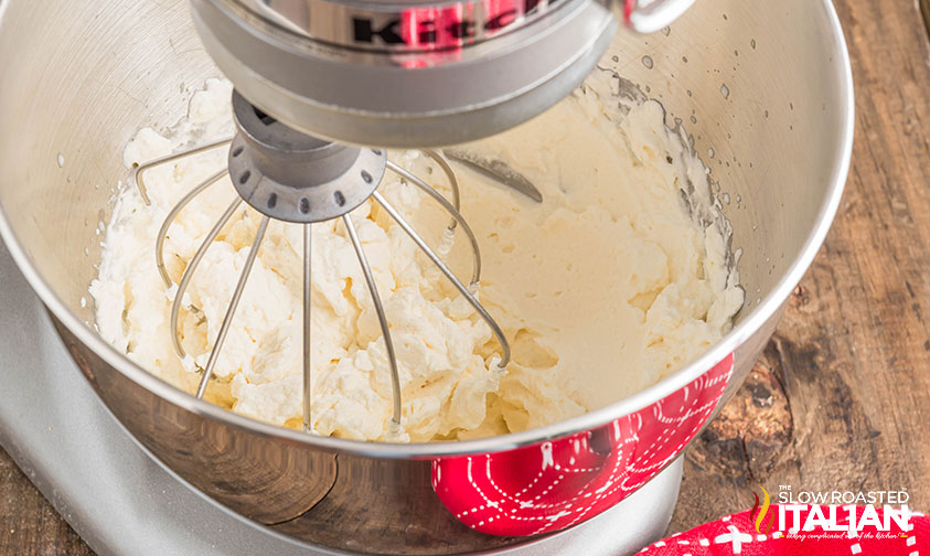 whisking maple syrup whipped cream in the bowl of a stand mixer