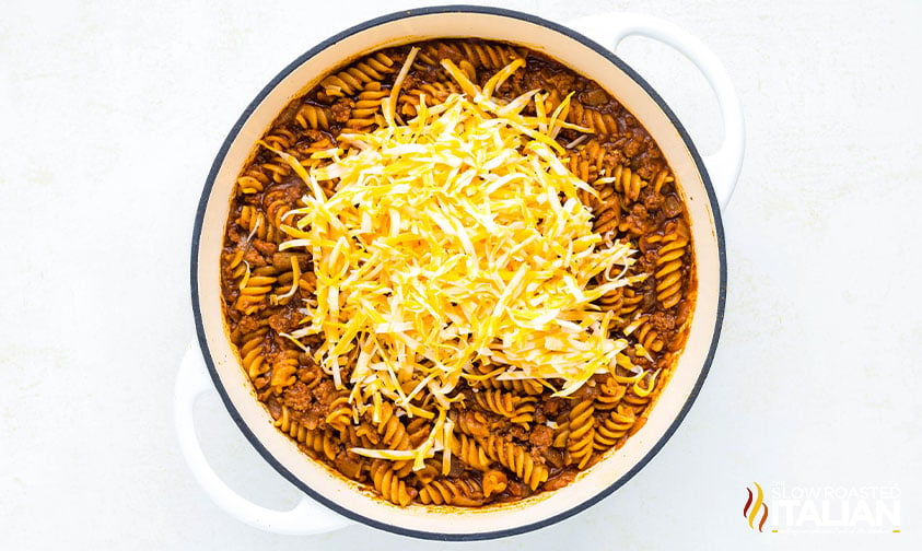 adding shredded cheese to enchilada pasta recipe