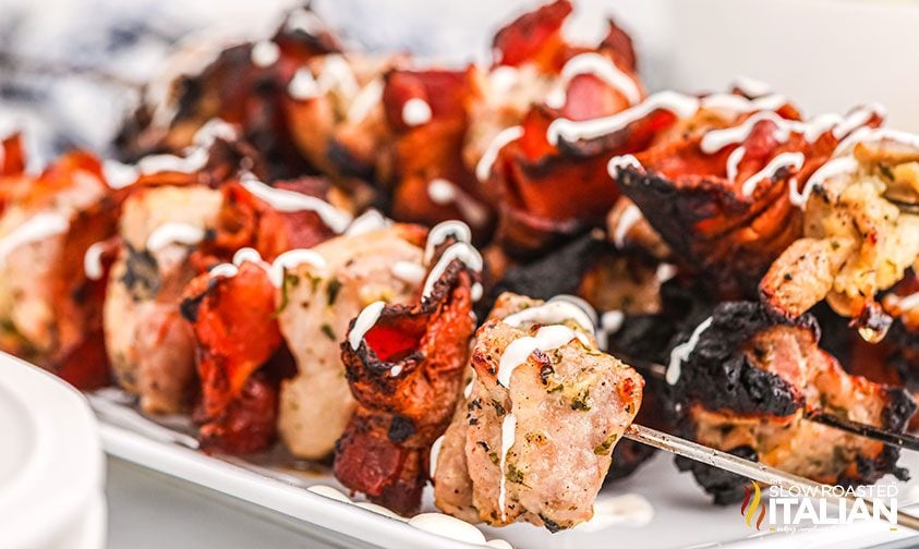 closeup: grilled chicken bacon skewers drizzled with ranch dressing