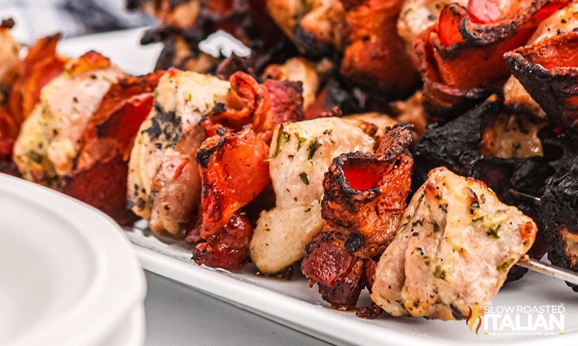 closeup: grilled chicken and crispy bacon on metal skewers