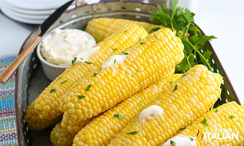 platter of corn on the cob with butter and fresh parsley