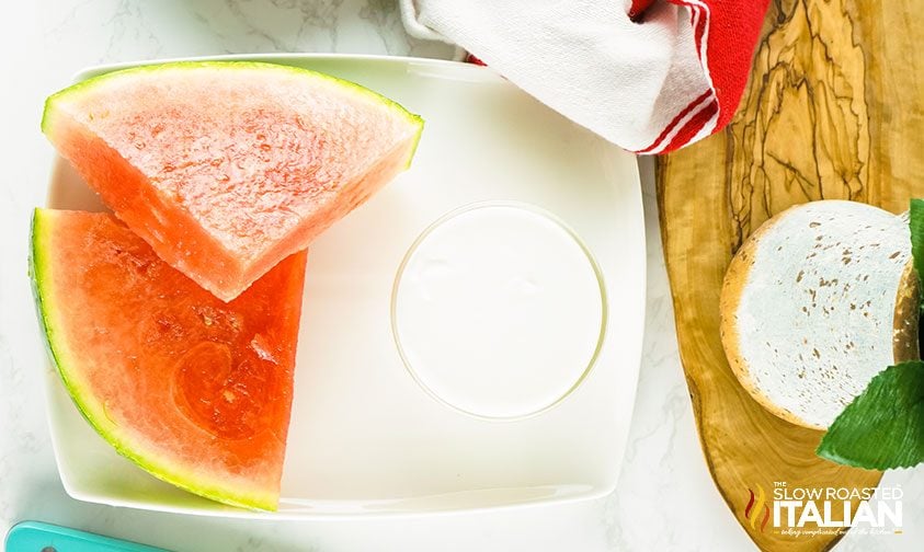 overhead: watermelon slices and cup of yogurt on plate