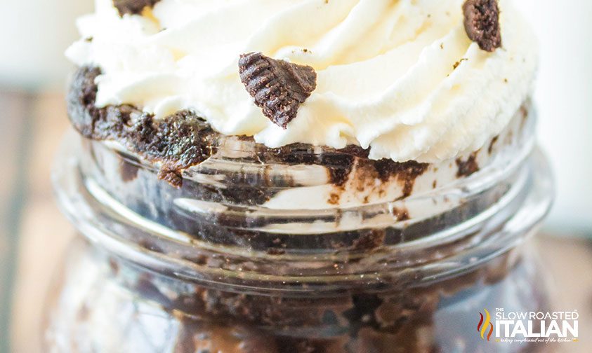 closeup: oreo cake in a mug topped with whipped cream and crushed cookies