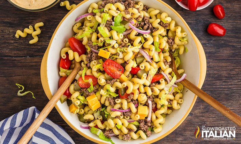 bowl of hamburger pasta salad tossed with wooden spoons