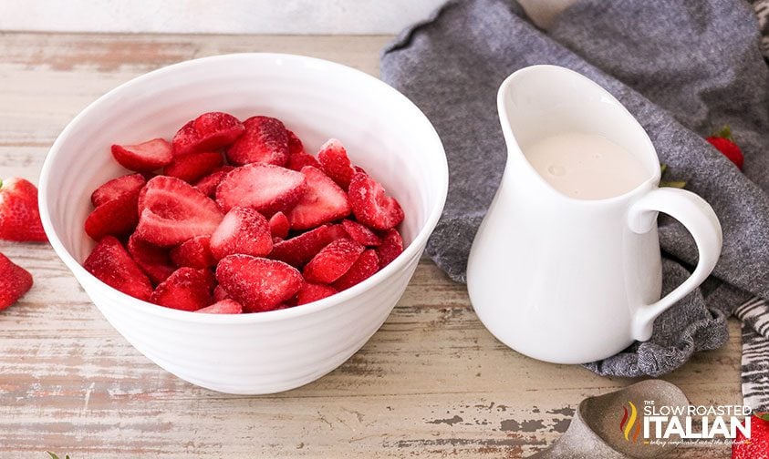bowl of frozen strawberry slices and small pitcher of coffee creamer