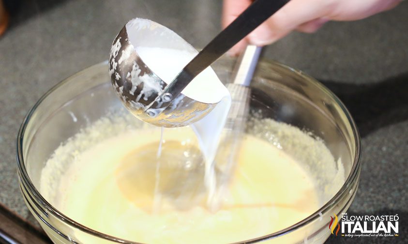 ladling hot cream into custard base while whisking