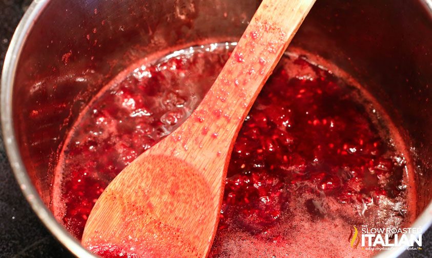 mashing wine and berries in a pot with a wooden spoon