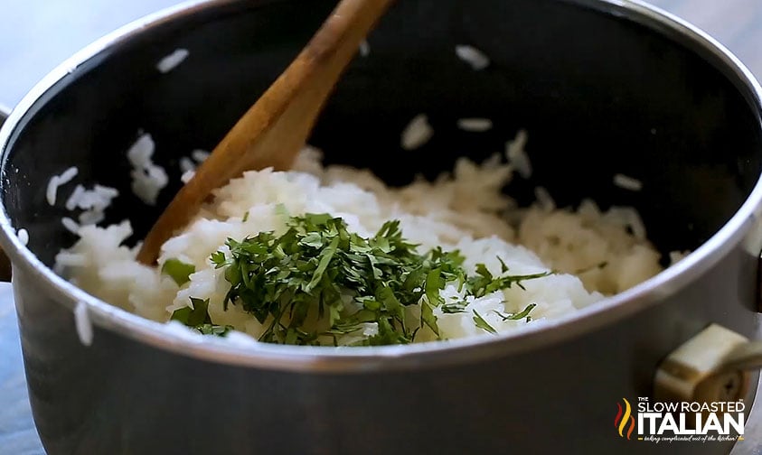 adding fresh cilantro to a pot of copycat chipotle rice