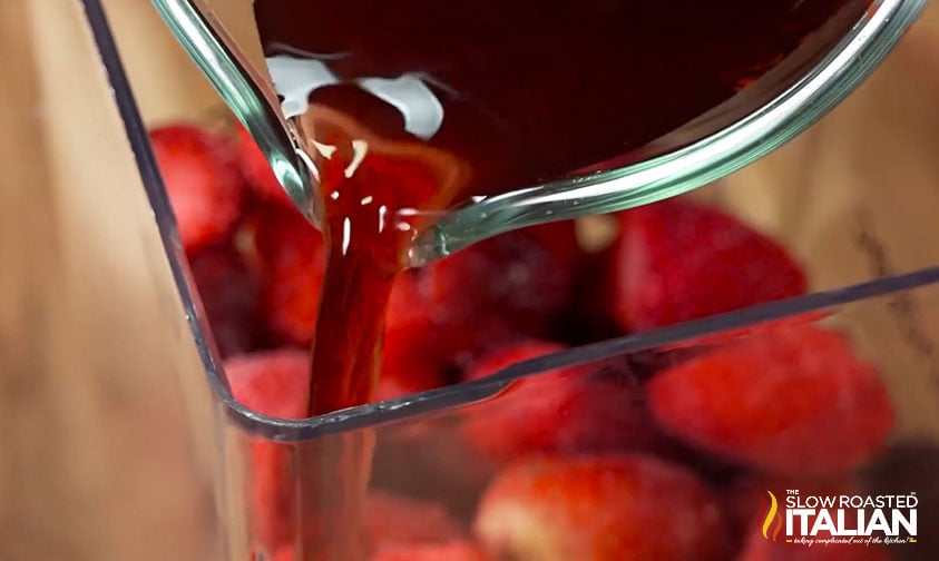 adding pomegranate juice to frozen strawberries in the blender