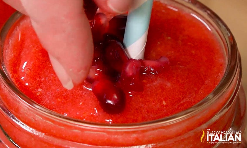 adding pomegranate seeds to the top of a skinny shake