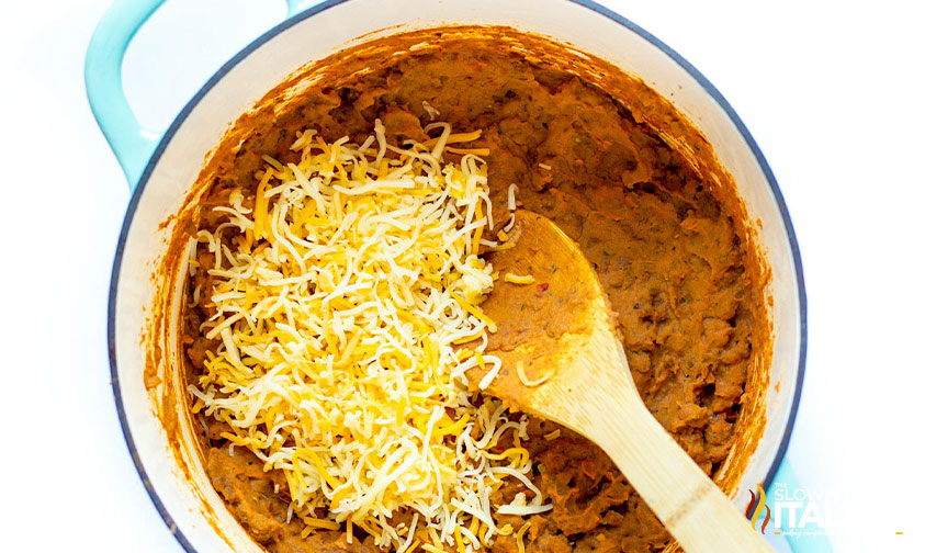 adding shredded cheese to refried bean casserole