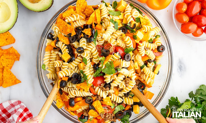 mixing taco pasta salad with wooden salad spoons