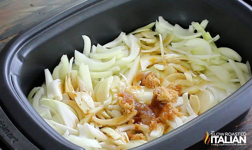 sliced onions in crockpot with brown sugar and sauces