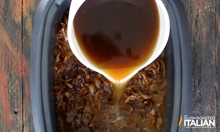 pouring beef stock over caramelized onions in slow cooker