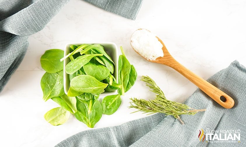 fresh spinach and rosemary with a wooden spoonful of coconut oil