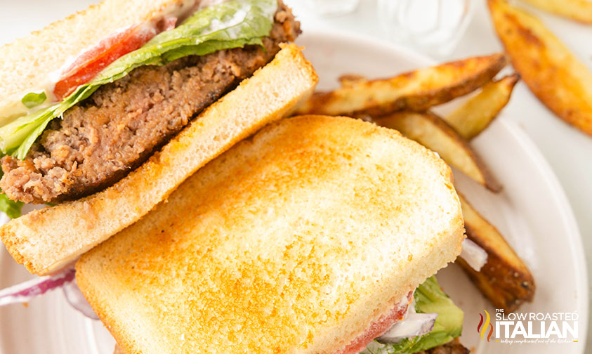 sliced meatloaf sandwich on a plate with potato wedges